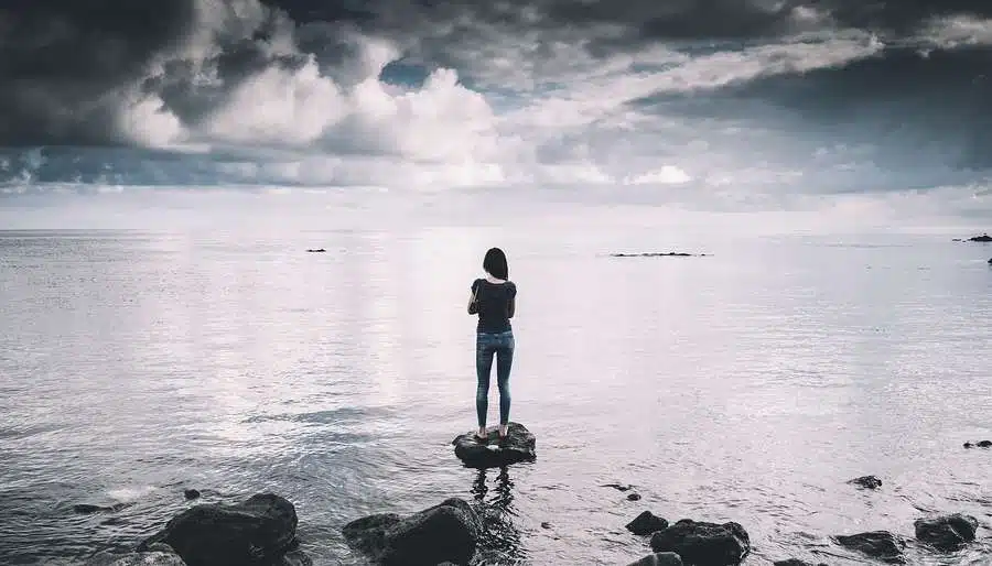 Woman Standing on Empty Beach looking at Horizon